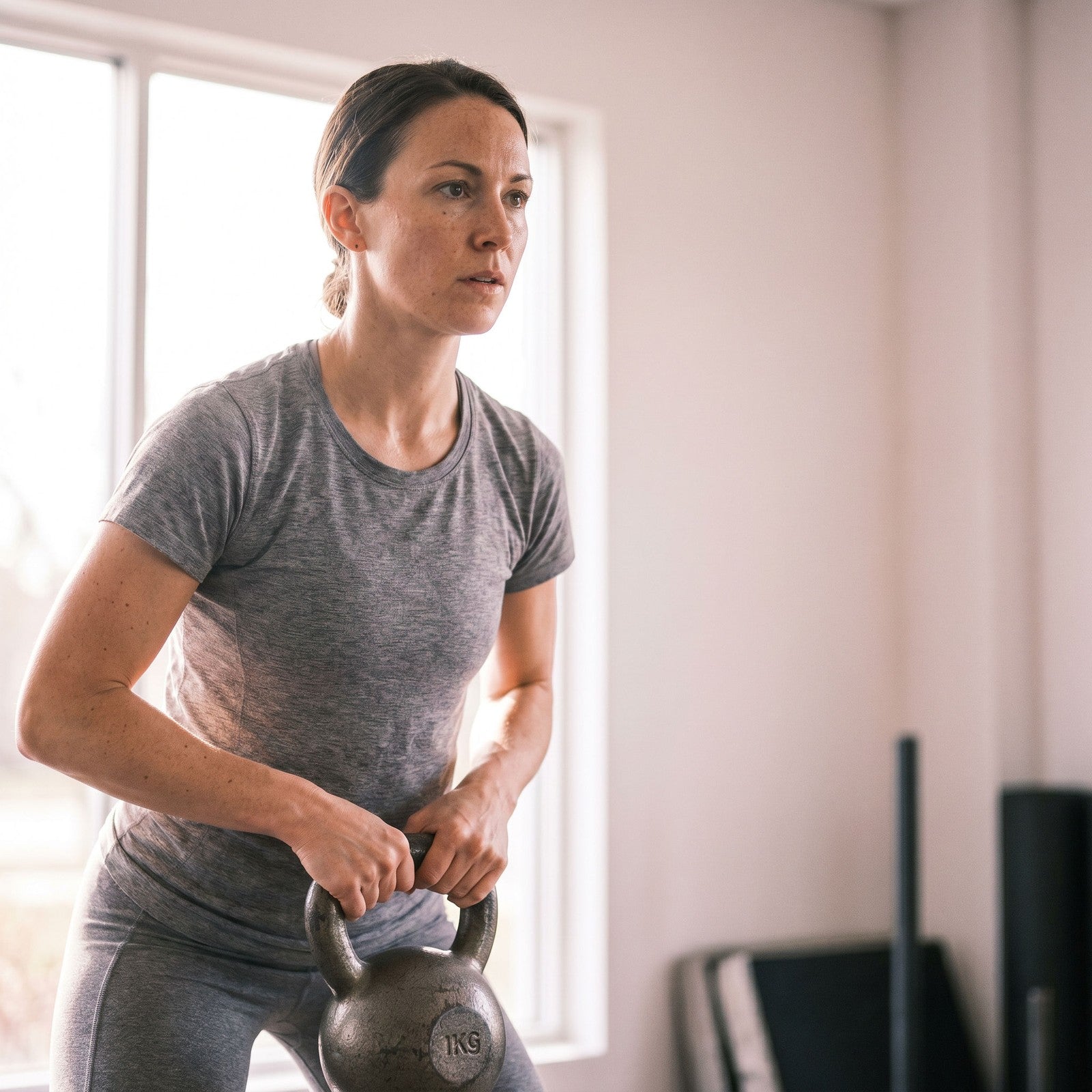 Woman focused mid workout, training with a kettlebell